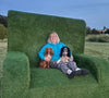 Tracy Ridley with her dogs Rosie and Barney sat on a giant grass seat at Ripley Castle Country Fair
