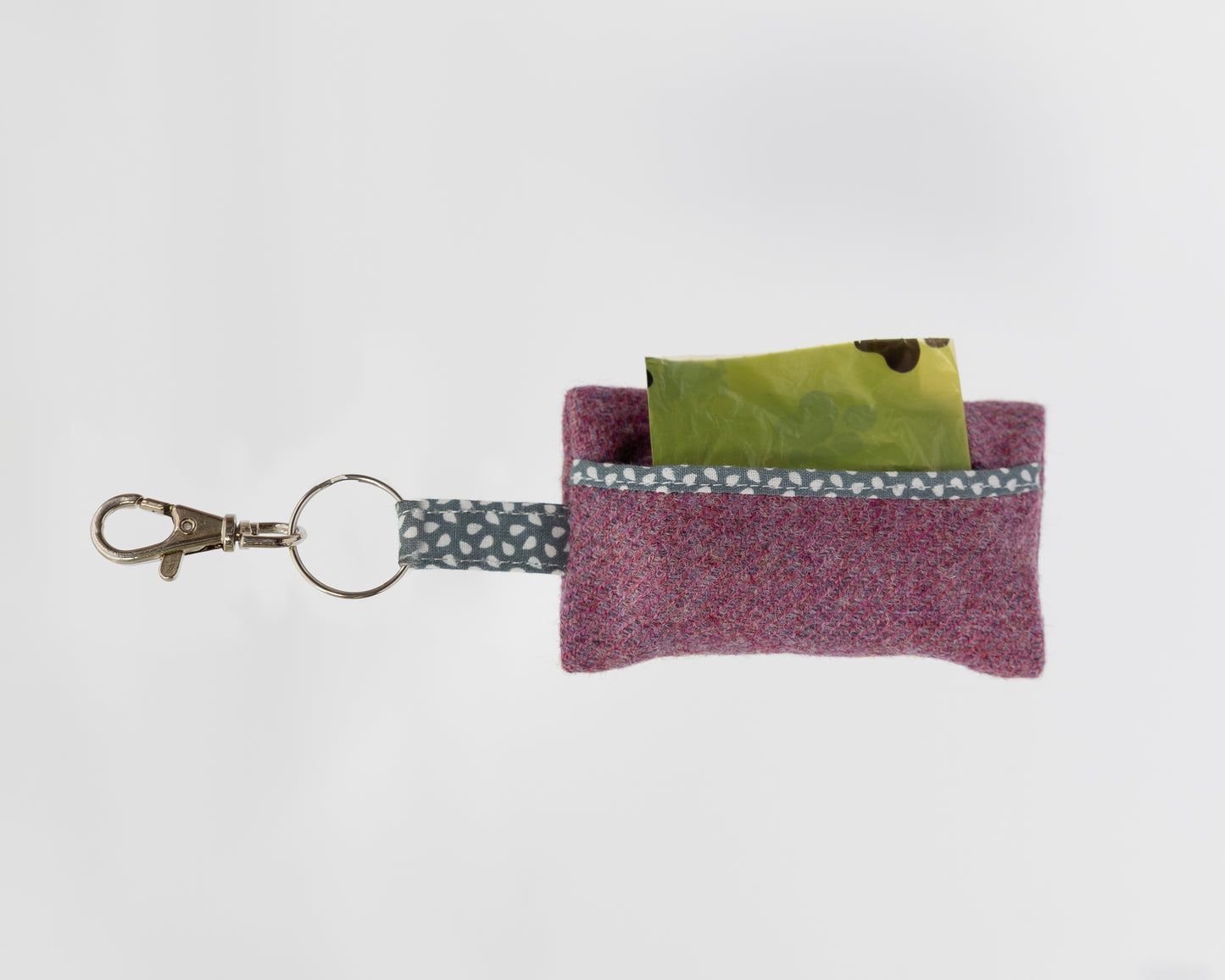 Small purple fabric pouch with a keychain and green card on a white background