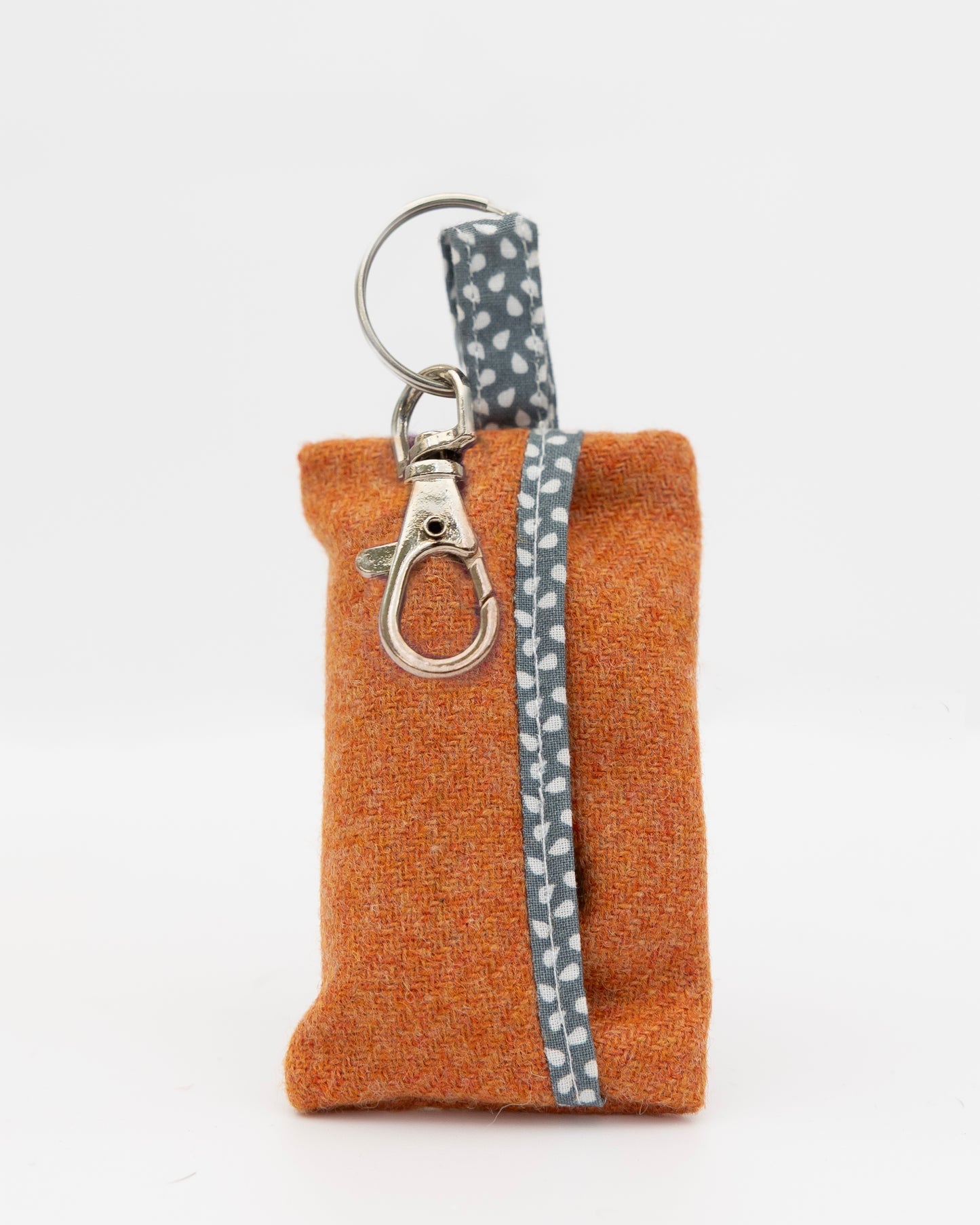 Small brown pouch with a keychain and gray patterned strap on a white background