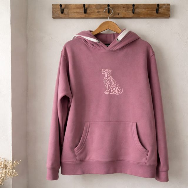 Purple hoodie with text on a wooden hanger against a beige wall