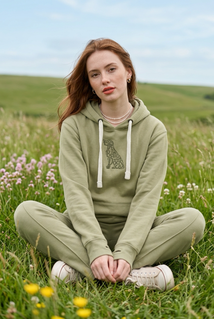 Woman sitting in a field wearing a green hoodie and pants.