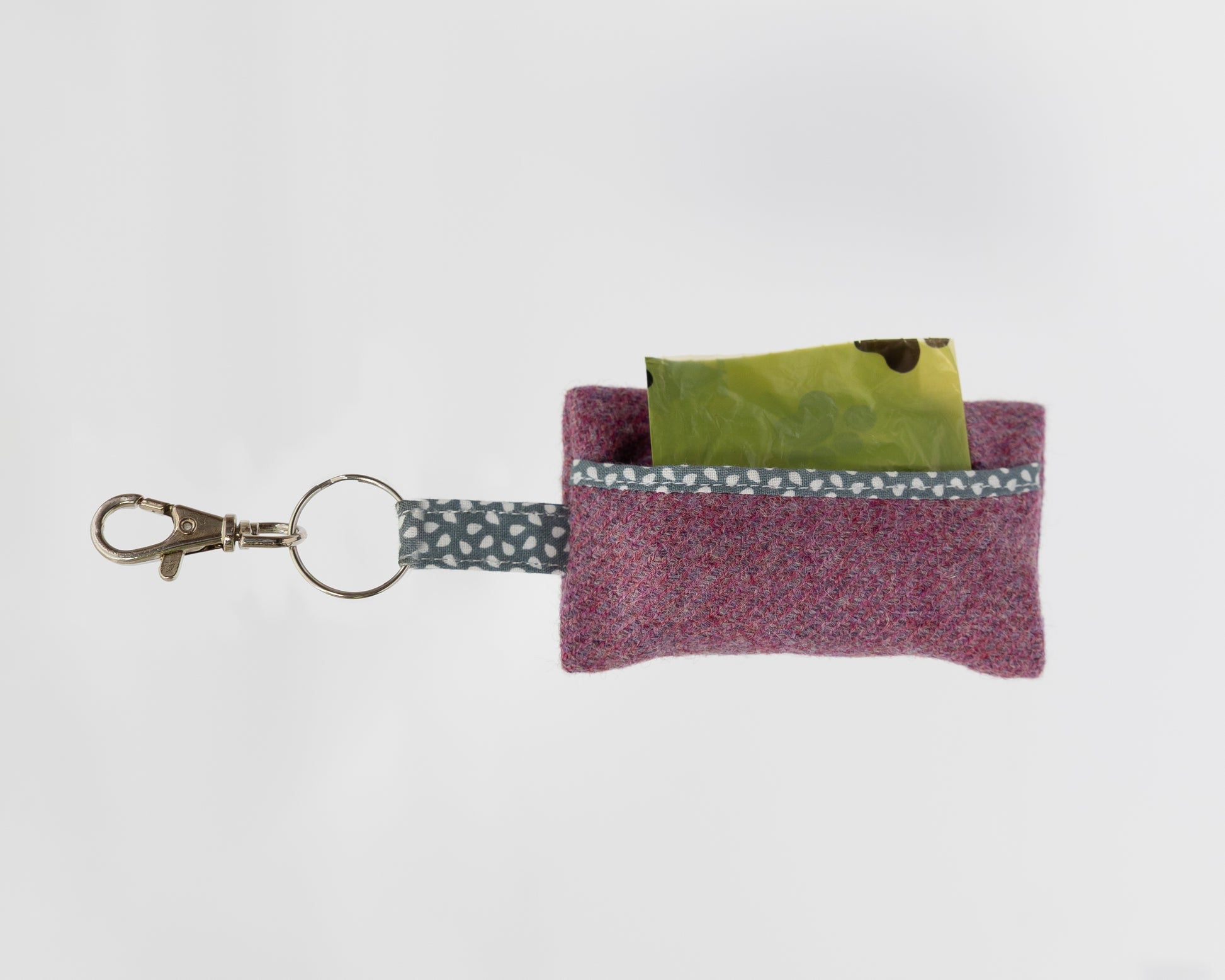 Small purple fabric pouch with a keychain and green card on a white background