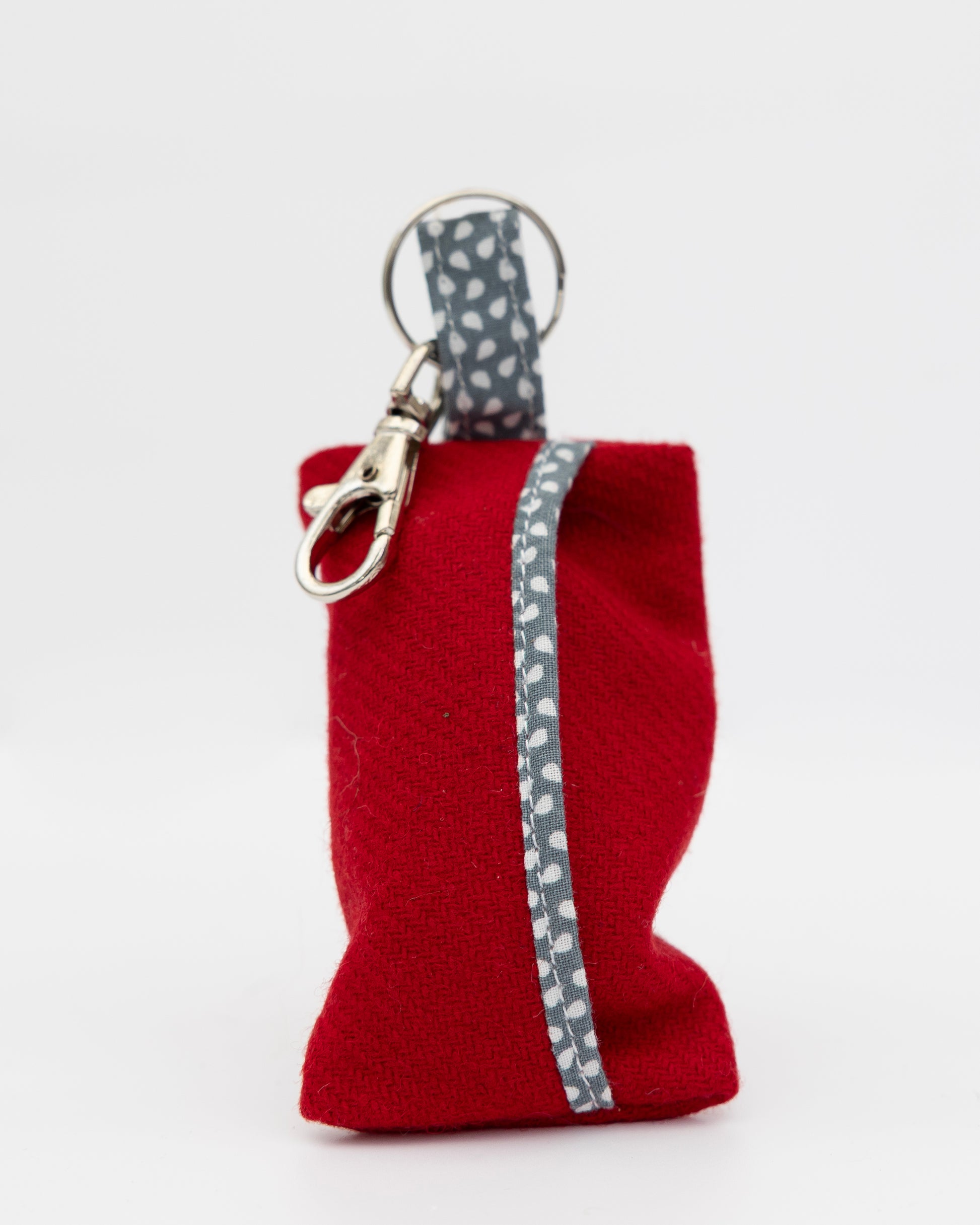 Red fabric pouch with a gray zipper and keychain clip on a white background